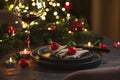 Christmas Table Setting with Tree-Shaped Napkin and Tealight Candles against Christmas lights Royalty Free Stock Photo