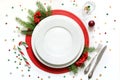 Christmas table setting with white dishware, silverware and red decorations on white background. Top view. Royalty Free Stock Photo