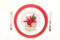 Christmas table setting with white dishware, silverware and red decorations on white. Top view. Copy space. Royalty Free Stock Photo