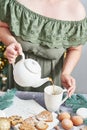 Christmas table setting. Woman pouring tea. Treats and food. Tea set and sweets on background of Christmas tree. Christmastime