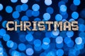 Christmas text on abstract blue bokeh balls background. Holiday letters on festive background Royalty Free Stock Photo