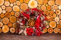 Christmas texture background of dry wooden log cabins and decorative wreath with cones, ribbons and berries Royalty Free Stock Photo