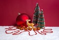 Christmas theme with miniature reindeer, decorated Christmas trees, presents and big bauble on red background Royalty Free Stock Photo