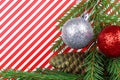 Christmas theme. Red-white striped background. Christmas Green cone and christmas ball . Spruce branch. Copy space Royalty Free Stock Photo