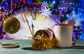 Christmas theme with toy ball, angel and mug on green wooden surface against nice clock background