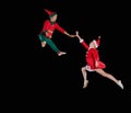 Christmas time, childhood, fairy tale. A young girl wearing a Santa`s costume and boy wearing elf costume flying Royalty Free Stock Photo