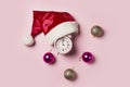 Christmas time.Christmas clock in a Santa Claus hat or cap on and christmas balls a pink background. The minute Royalty Free Stock Photo