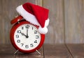 Christmas time concept, red santa hat alarm clock on a wooden background Royalty Free Stock Photo