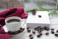 Christmas time concept: a white cup of coffee stands on a white wooden table next to a white open book and colorful candy against Royalty Free Stock Photo