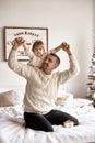 Dad and his little daughter have fun and play sitting on the bed in a bedroom with Christmas decor Royalty Free Stock Photo