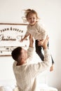 Dad and his little daughter have fun and play sitting on the bed in a bedroom with Christmas decor Royalty Free Stock Photo