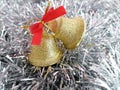 Christmas Time. Golden jingle bells with red ribbon on a silver background.The main subject in the middle. Royalty Free Stock Photo