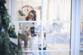 Christmas time. Happy family with two little kids gathered at window at home decorating xmas tree Royalty Free Stock Photo