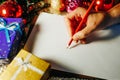 christmas time human hand writing unrecognizable with red pencil on white paper Royalty Free Stock Photo