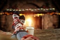 Christmas time, legs in winter socks. Space for your text or decoration. Old fireplace wall background.