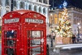 A red telephone booth in front of an illuminated Christmas Tree in Central London, UK Royalty Free Stock Photo