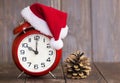 Christmas time. Red santa hat alarm clock and pine tree cone