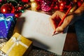 christmas time unrecognizable man hand writes a letter with a red pencil on a sheet of paper.