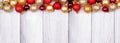 Christmas top border of red and gold ornaments on a winter white wood banner background Royalty Free Stock Photo