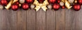 Christmas top border of red and gold ornaments and ribbon on a dark wood banner background Royalty Free Stock Photo