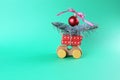 Christmas, a toy car with wrapped gifts and spruce branches, a red ball with a bow, a toy house on a green background Royalty Free Stock Photo