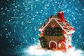 Christmas toy in the form of a gingerbread house illuminated from below on a blue shiny background with a copy space. Electoral Royalty Free Stock Photo