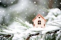 Christmas toy house on a natural natural background of a real fir in the snow, toned. Concept of winter, Christmas, new year Royalty Free Stock Photo