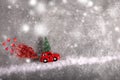 Christmas toy red car with fir tree on the roof on snow road with red sequin smoke.