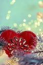 Christmas toy red heart with ornament on the snow. Luminous garland and pine branches on ice crystals. Toned image. Copy space. Royalty Free Stock Photo