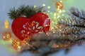 Christmas toy red heart with ornament on the snow. Garland and pine branches on ice crystals. Blurred background and bokeh. Royalty Free Stock Photo