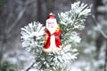 Christmas toy red Santa Claus on a natural branch with pine tree needles in the snow background. Royalty Free Stock Photo