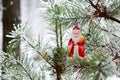 Christmas toy red Santa Claus on a natural branch with pine tree needles in the snow background. Concept for New Year, Christmas Royalty Free Stock Photo