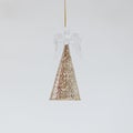 Christmas toy in the shape of a fragile angel in a golden shiny skirt on the light background