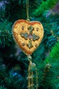 Christmas toy in the shape of a heart on a background of green artificial spruce