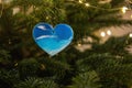Christmas toy in the shape of a heart with the image of waves of the blue sea hangs on a green tree Royalty Free Stock Photo