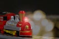 Christmas toy train on the background of out-of-focus lights from a garland. Close-up, selective focus, dark background Royalty Free Stock Photo