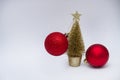 Christmas toy, two shiny red balls and a golden Christmas tree. New Year. On a gray background Royalty Free Stock Photo
