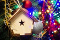 Christmas toy wooden house on the Christmas tree on the colorful lighting background. Beautiful Christmas decorations. Cool bright Royalty Free Stock Photo