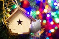 Christmas toy wooden house on the Christmas tree on the colorful lighting background. Beautiful Christmas decorations. Cool bright Royalty Free Stock Photo