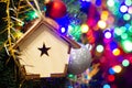 Christmas toy wooden house on the Christmas tree on the colorful lighting background. Beautiful Christmas decorations. Cool bright Royalty Free Stock Photo