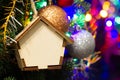 Christmas toy wooden house on the Christmas tree on the colorful lighting background. Beautiful Christmas decorations. Cool bright Royalty Free Stock Photo