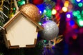 Christmas toy wooden house on the Christmas tree on the colorful lighting background. Beautiful Christmas decorations. Cool bright Royalty Free Stock Photo