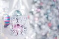 Christmas toys balls silver blue pink in white openwork cage on the background of Christmas lights Royalty Free Stock Photo