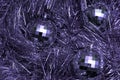 Christmas toys in the form of disco balls lie on a festive silver tinsel, top view, purple color