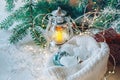 Christmas toys in a knitted hat lie under the Christmas tree next to a decorative stylized lamp. A Christmas card for