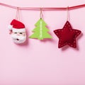 Christmas toys and a tag with text hang on a decorative ribbon on a pink background with copy space