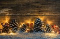 Wintry Christmas decoration with natural pine cones, red berries, lights, snow and wood background Royalty Free Stock Photo