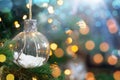 Christmas transparent bauble hanging on the brunch with bokeh and lights. Copy space