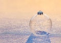 Christmas transparent glass ball with snowflakes on sunset snow