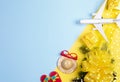 Christmas travel concept with fir branches, snow, gift boxes, toy flops, hat, sunglasses, airplane on yellow-blue